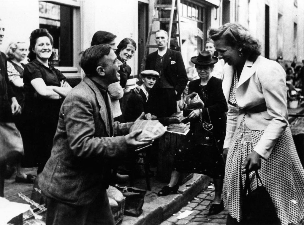 « Marché noir : une jeune femme achète du pain dans la rue des Radis à Bruxelles, 1943 ». Droits réservés (CegeSoma : n°28437).
