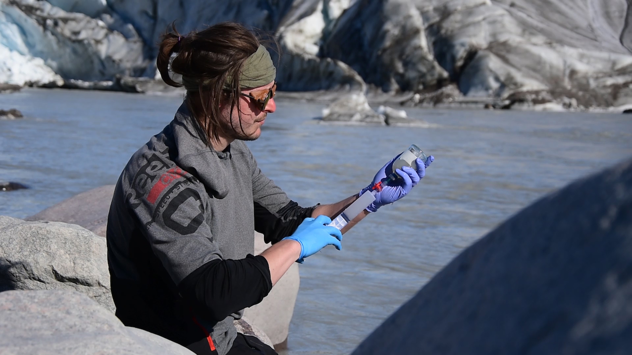 Prélèvement d'échantillon d'eau de fonte au Groenland par Guillaume Lamarche-Gagnon. © Marie Bulinova